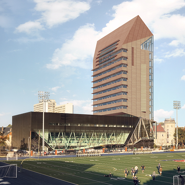 The Academic Wood Tower stands beyond a group of football players playing on  the field. 