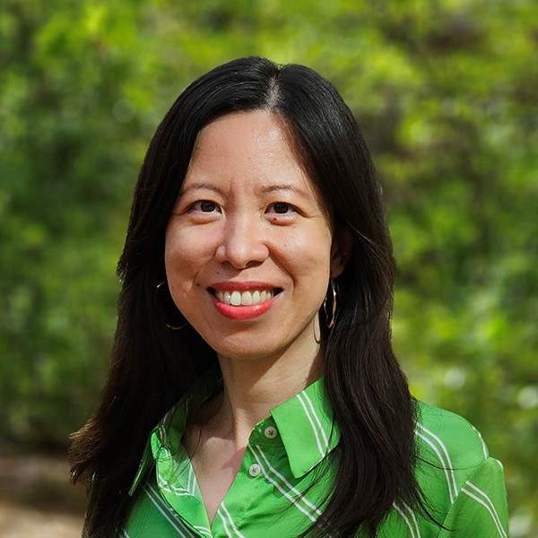 A woman in a green shirt smiles.
