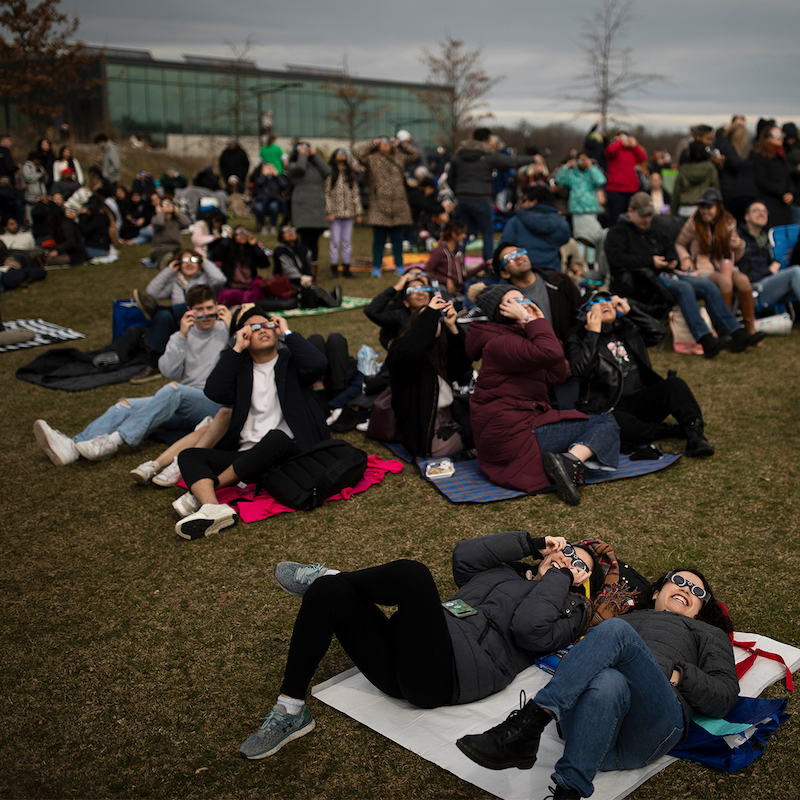 Students gather on U of T campus in MIssissauga to watch the eclipse while wearing protective glasses.